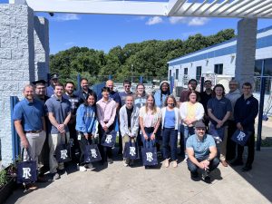 Hayward Industries team gathers a group of URI alumni outside for a photo.